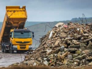 camion giallo con cassone scarrabile e diversi rifiuti e macerie edili