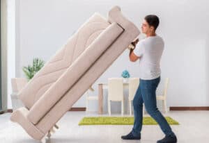 uomo solleva un divano per lo spostamento dei mobili in casa