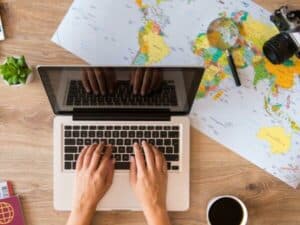 Ragazza scrivere al computer con mappa del mondo e passaporto vicino per il trasloco internazionale