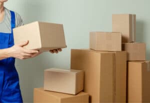 diversi pacchi per il trasloco e un traslocatore che trasporta uno scatolone