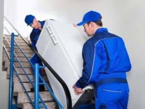 traslocatori mentre trasportano un frigorifero per le scale