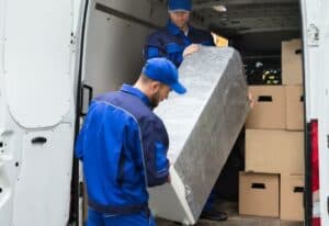 trasportatori durante il carico di un frigorifero imballato in un furgone