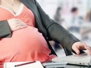 Donna in stato di gravidanza con computer e quaderno per organizzare il trasloco