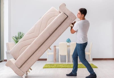 uomo solleva un divano per lo spostamento dei mobili in casa