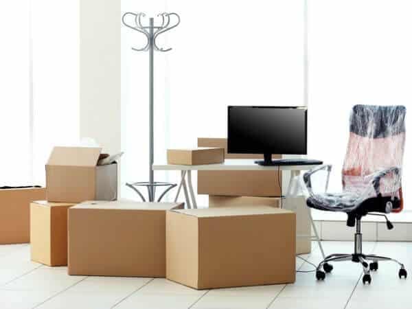 Stanza di un ufficio con scatoloni, una sedia imballata e monitor