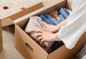 una donna inserisce un capo d'abbigliamento all'interno di uno scatolone per trasloco